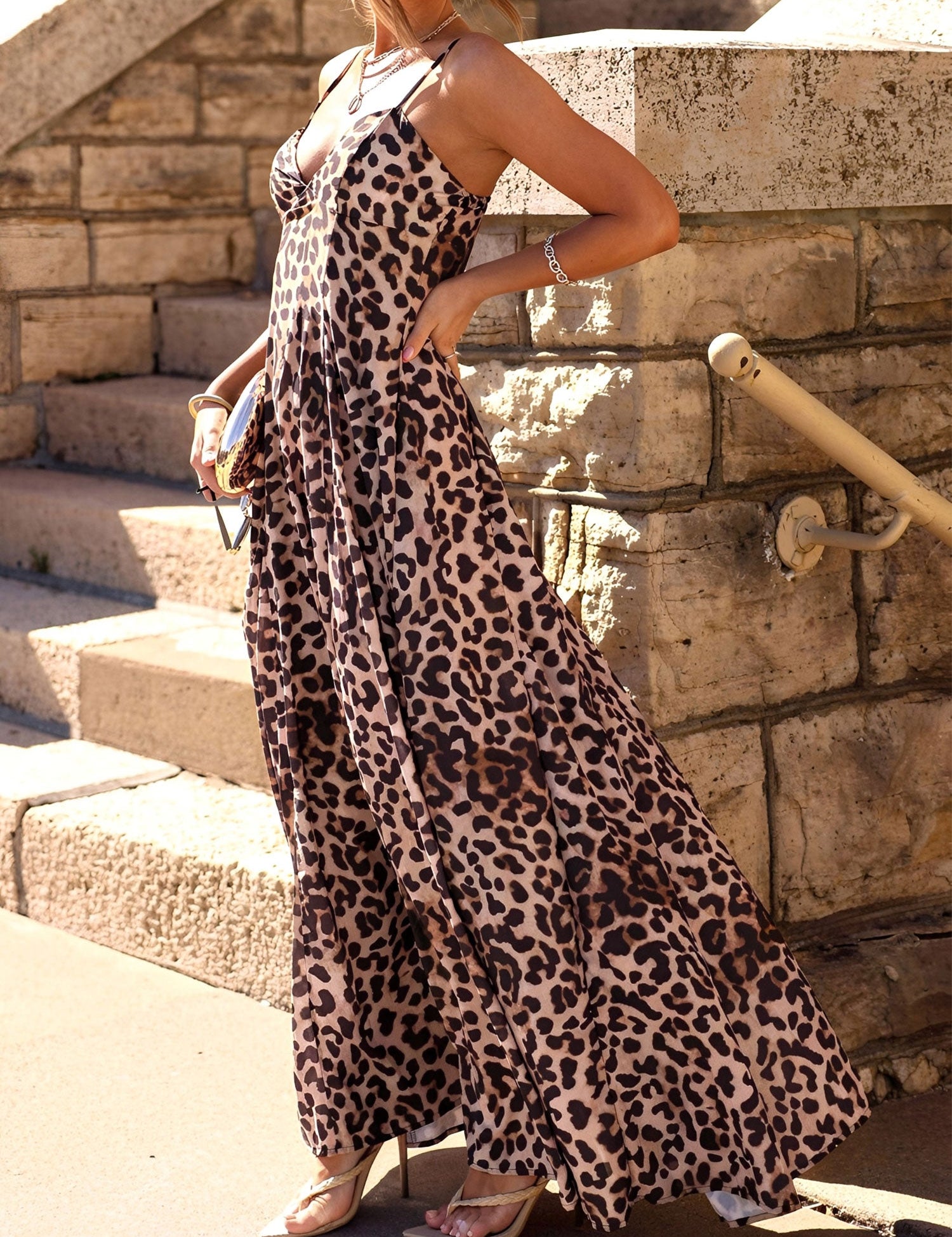 Woman wearing a leopard print dress standing on stone steps.